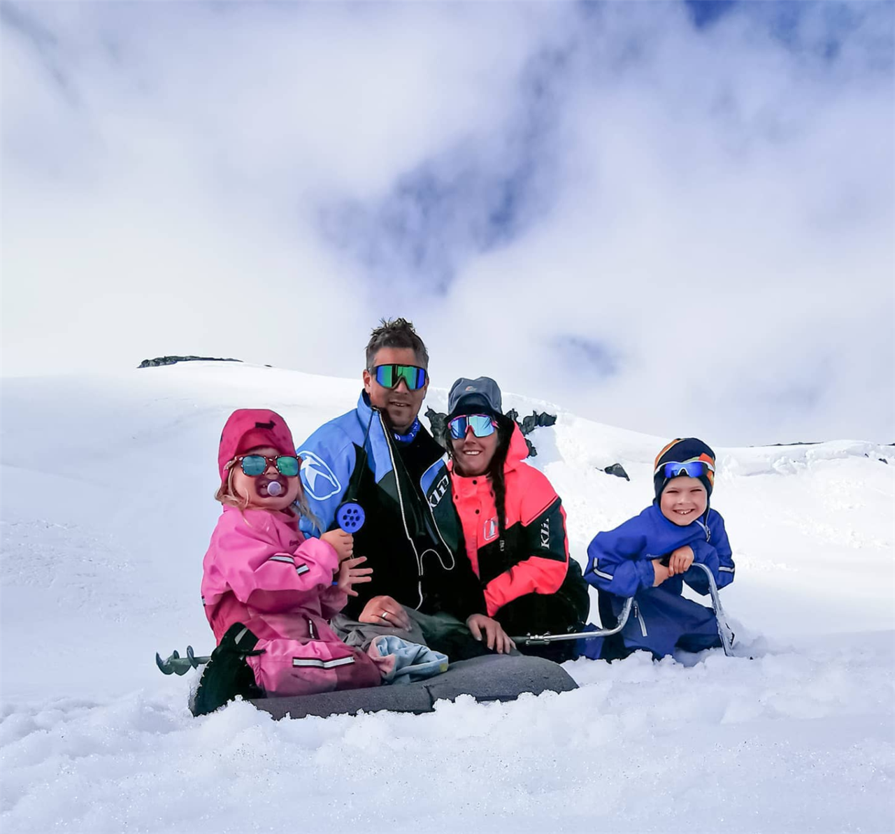 Familien fra Fjelltun sitter i snøen og smiler - Klikk for stort bilde